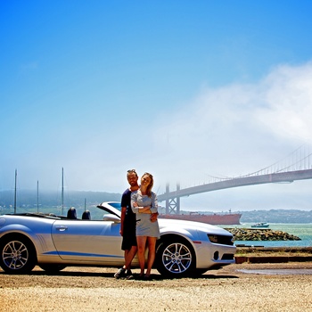 Ungt par foran bil og Golden Gate i San Francisco, USA