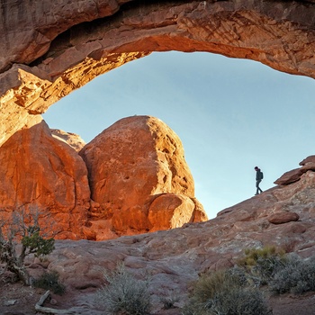 Mand på vandretur i Arches National Park, Utah, USA - Foto Intricate Explorer Unsplash