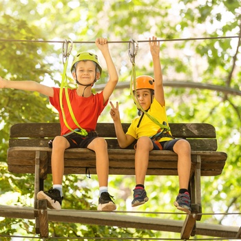 Børn i adventurepark og prøve zipline / klatrebane i træerne