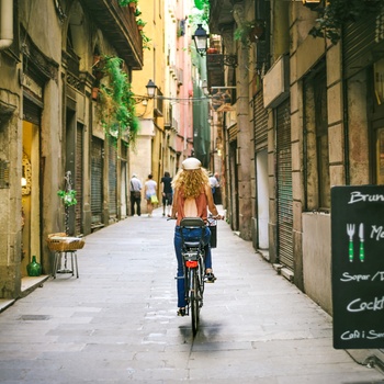 Kvinde cykler gennem de gamle gader i Barcalona, Spanien