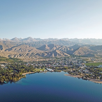 Luftfoto af feriebyen Cholpon-Ata ved Issyk-Kul søen med Tian Shan-bjergene i baggrunden - Kirgisistan