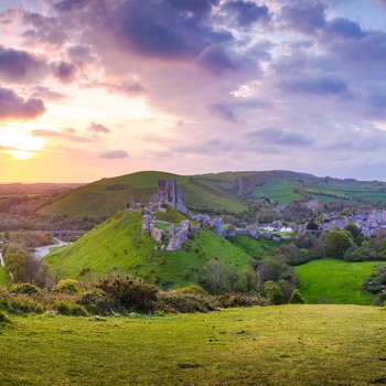  Corfe Castle og slotsruinen i solnedgang, Dorset i Sydengland