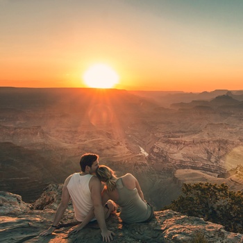 Yngre par nyder solnedgangen over Grand Canyon