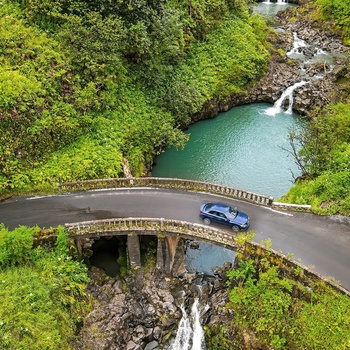 Personbil på vej over bro og lille vandfald på Maui, Hawaii