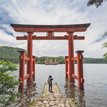 Turist tager billeder under en torri gate ved bredden af Lake Ashi med Mt. Fuji i baggrunden, Japan 