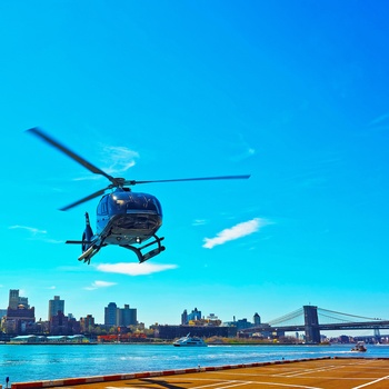 Helikopter ved East River med Manhattan Bridge i baggrunden i New York, USA