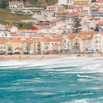 Bølger slår op på stranden i kystbyen Nazare, Portugal