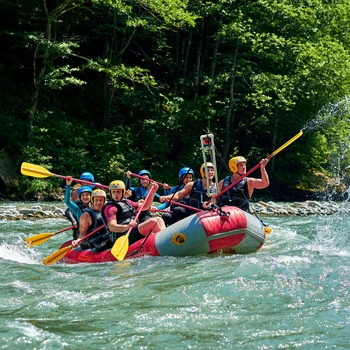 Gruppe på raftingtur ned ad flod med små rapids