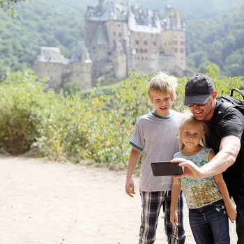 Far, søn og datter tager selfie foran slot i Tyskland