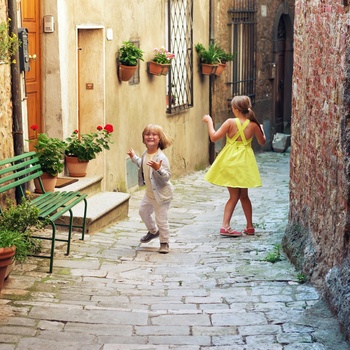 Børn hygger sig i gammel bydel i en by i Toscana, Italien