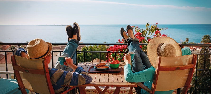 Ungt par nyder morgenmad på balkon med havudsigt