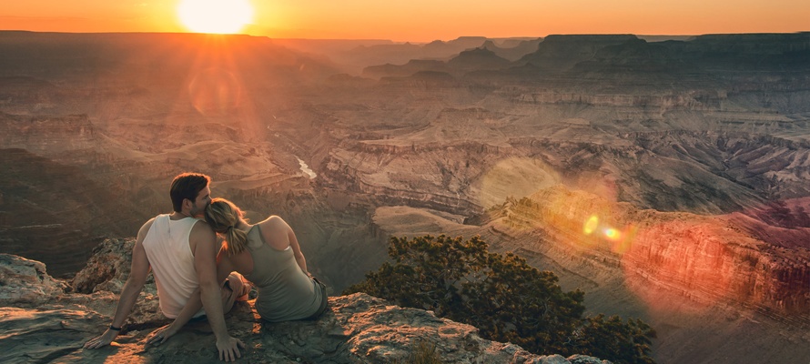 Yngre par nyder solnedgangen over Grand Canyon