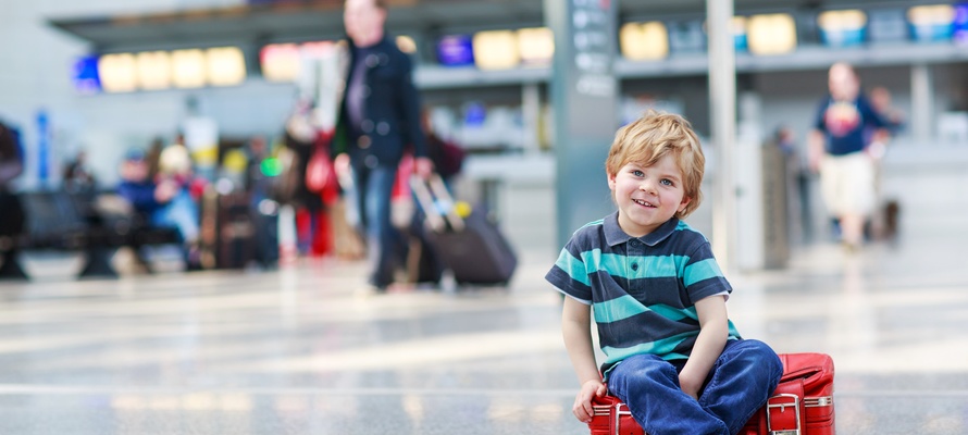 Lille dreng på sin kuffert i lufthavn