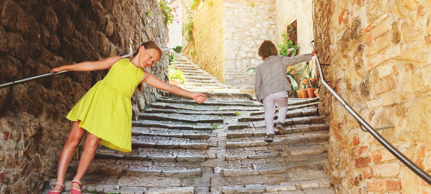 Børn hygger sig i gammel bydel i en by i Toscana, Italien