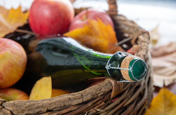 En flaske cider i en kurv med æbler fra Normandiet