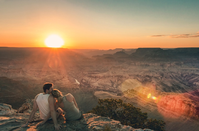 Yngre par nyder solnedgangen over Grand Canyon