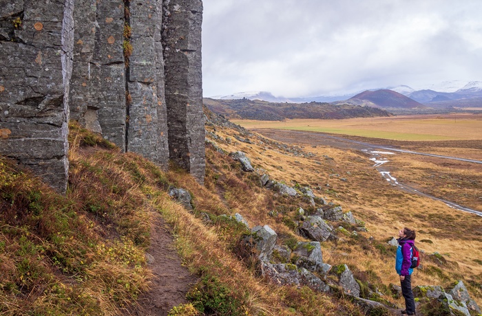 Turist kigger op på Gerðubergs basaltklipper i det vestlige Island