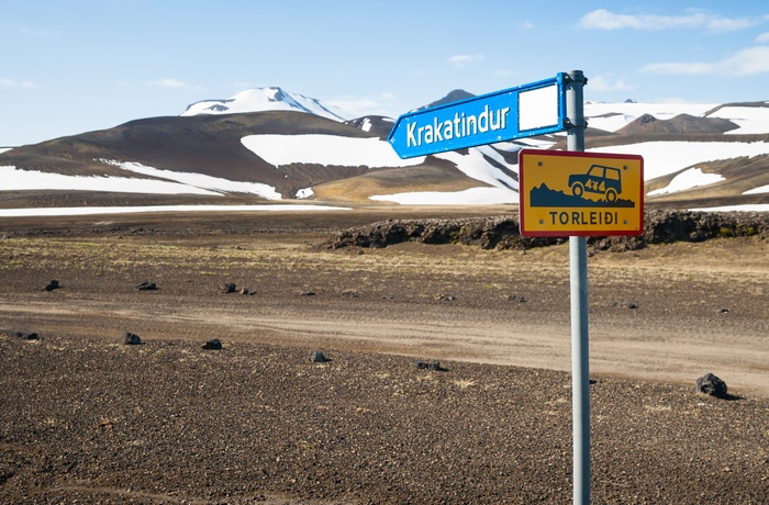 Islands højland med sneklædte bjerge og vejskilt i forgrunden