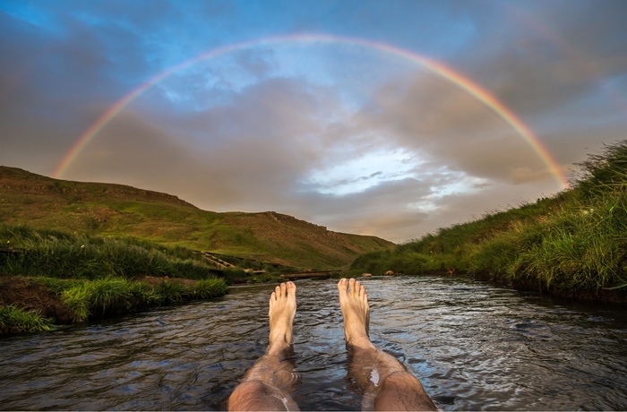 Regnbue over den varme flod i dalen Reykjadalur nær Reykjavik, Island