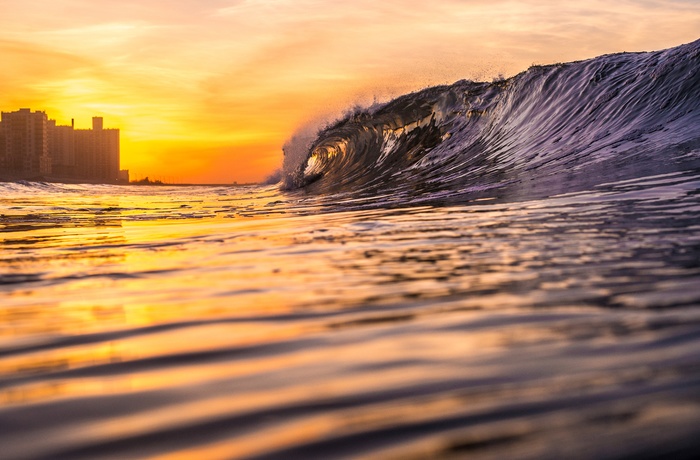 Stor bølge i solnedgang mod Rockaways Beach i Queens, New York City i USA