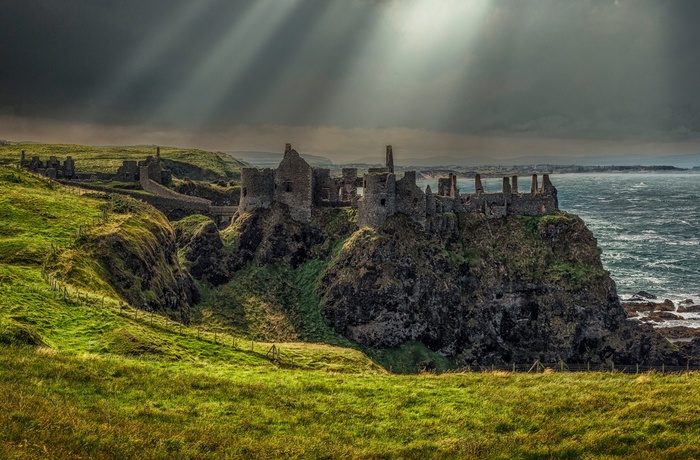 Nordirland, County Antrim, Bushmills - solen bryder gennem skyerne over Dunluce Castle