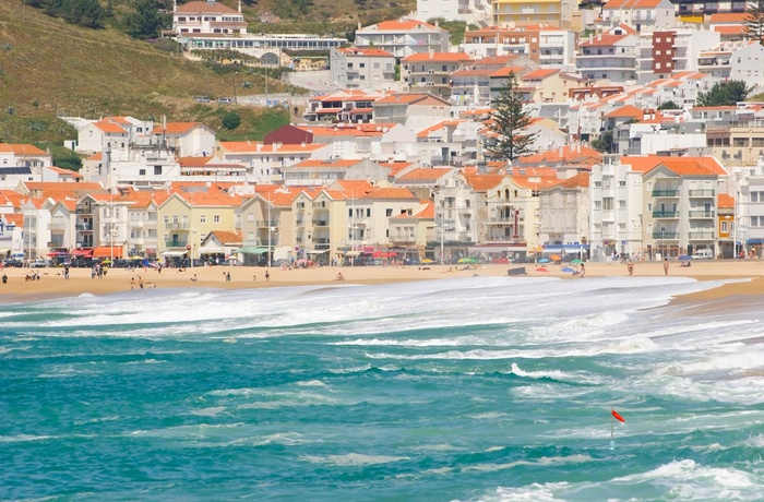Bølger slår op på stranden i kystbyen Nazare, Portugal