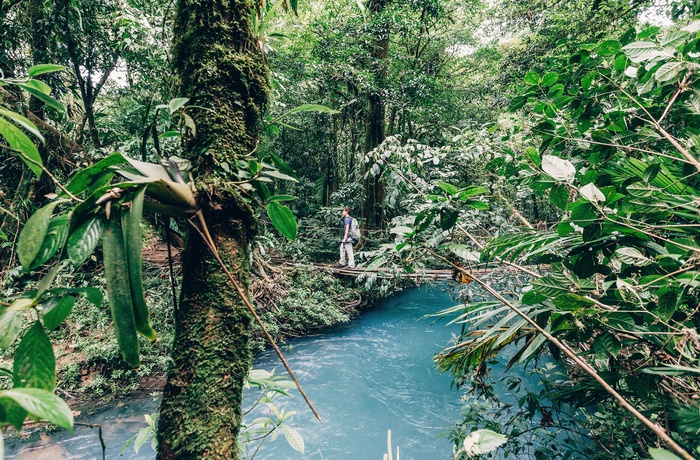 Kvinde på vej over lille flod og gennem gennem Tenorio Volcano National Park - Costa Rica