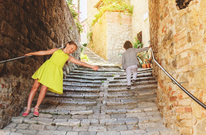 Børn hygger sig i gammel bydel i en by i Toscana, Italien