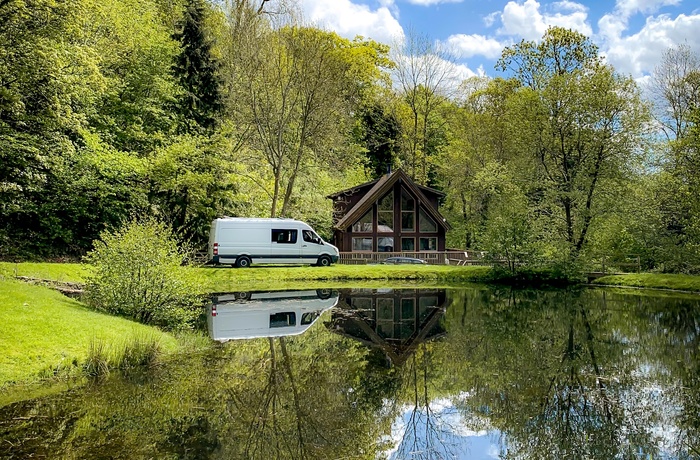 Autocamper parkeret ved sø og gammelt hus i Wales