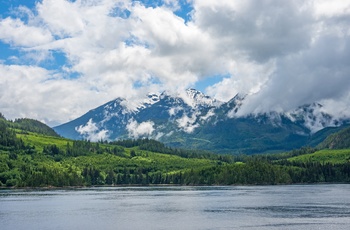 Frodig skovområder og snedækkede bjergtinder i baggrunden langs Inside Passage i British Columbia