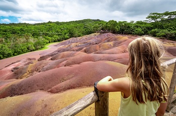 Lille pige beundrer de orangefarvede jordarter i Chamarel Seven Coloured Earth Geopark i Mauritius