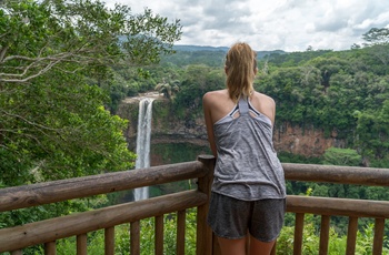 Ung kvinde nyder udsigten til vandfaldet Chamarel Waterfall i Mauritius