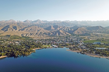 Luftfoto af feriebyen Cholpon-Ata ved Issyk-Kul søen med Tian Shan-bjergene i baggrunden - Kirgisistan