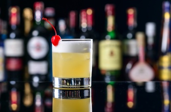 Cocktailen New York Sour med spiritusflasker i baggrunden