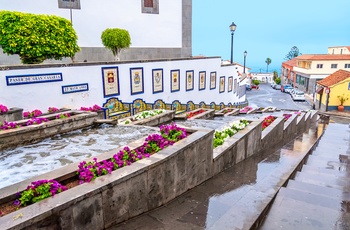 Det lille kunstige vandfald gennem en stejl gade i bjergbyen Firgas, Gran Canaria i Spanien