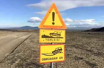 Vej gennem Islands højland og advarselsskilt i forgrunden