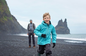 Far og søn på Reynisfjara stranden ved klipperne Reynisdrangar, Island