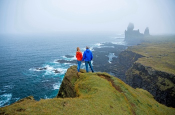 Ungt par kigger på basaltklippen Lóndrangar på Snæfellsnes halvøens kyst, Island