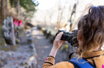Turist tager billeder i Kanmangafuchi Abyss-kløften med 70 Jizo-statuer - Japan