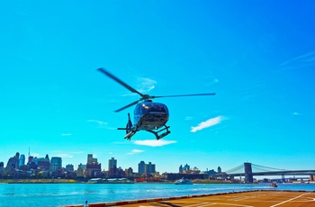 Helikopter ved East River med Manhattan Bridge i baggrunden i New York, USA