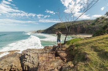 Ung mand tager billeder af kyststrækning i Noosa National Park, Queensland