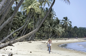 Ung pige på cykel langs strand ved Mission Beach - Queensland