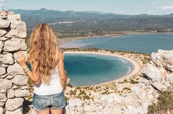 Ung kvinde nyder udsigten til Voidokilia-stranden på Peloponnes - Grækenland